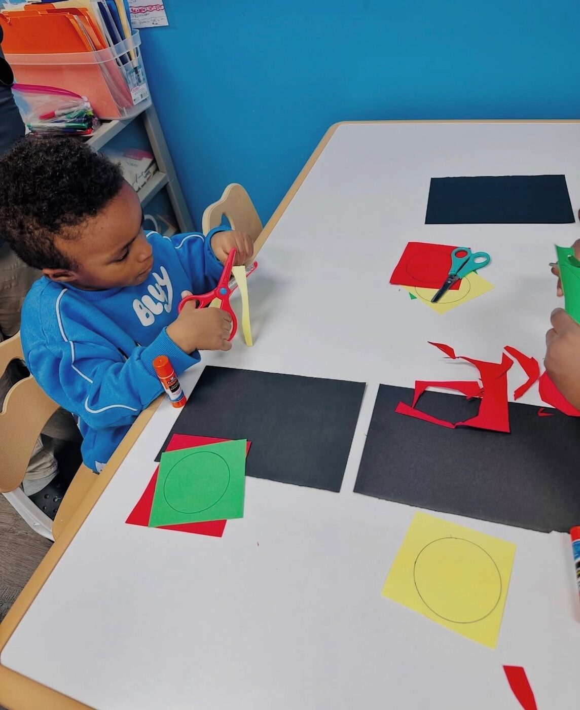 A focused child practicing fine-motor skills with scissors in Pre-K